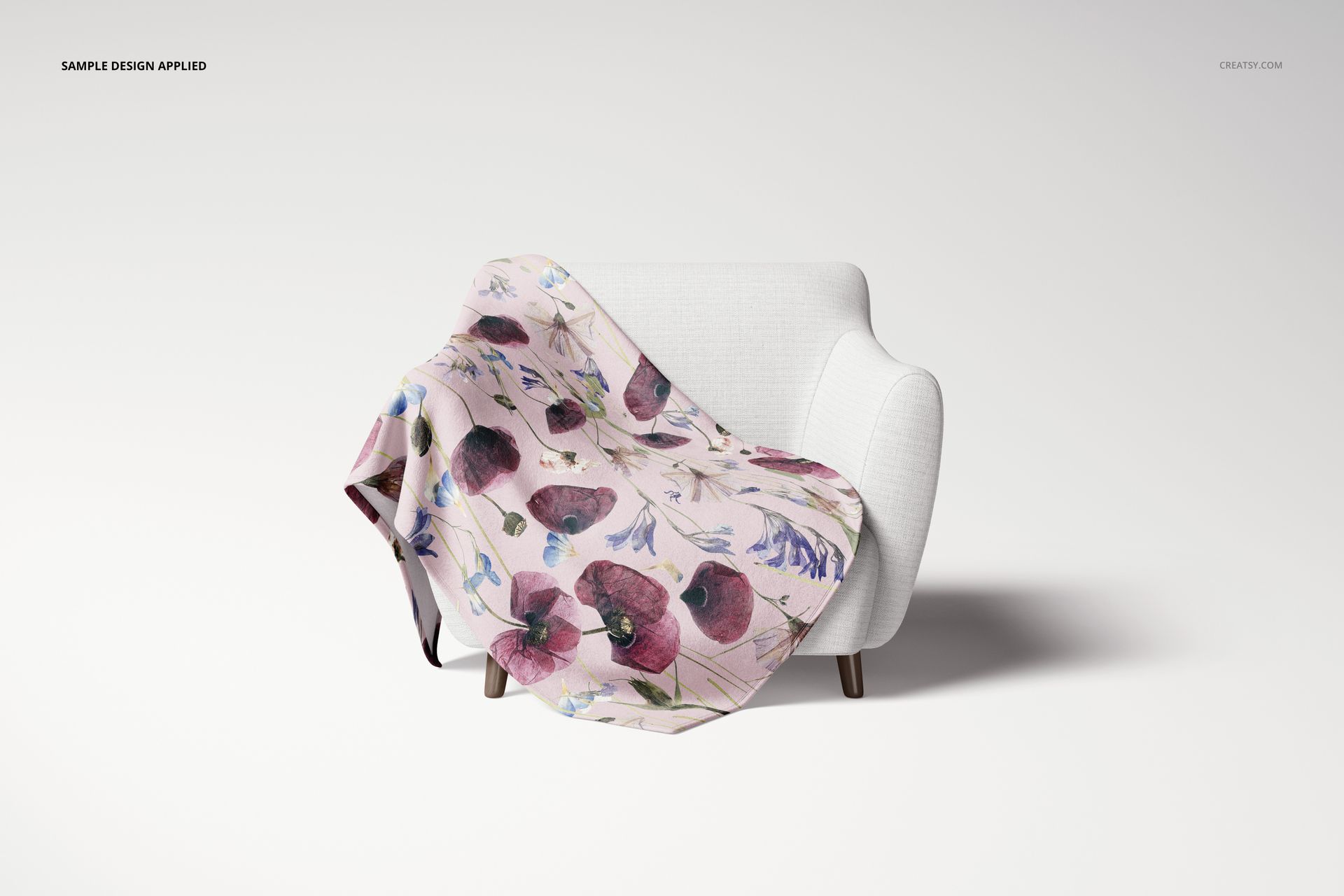 Floral fleece throw blanket mockup displayed on a white chair, featuring pink and purple flowers, front perspective.