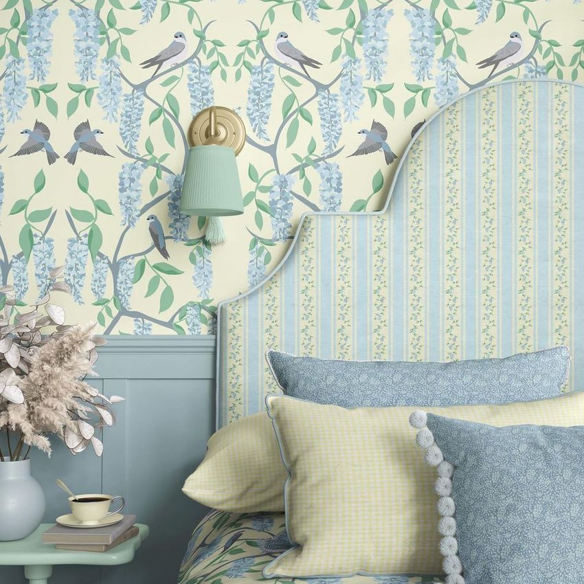 A mockup of a bedroom features patterned pillows, a curved headboard, and wallpaper with bird and floral illustrations.