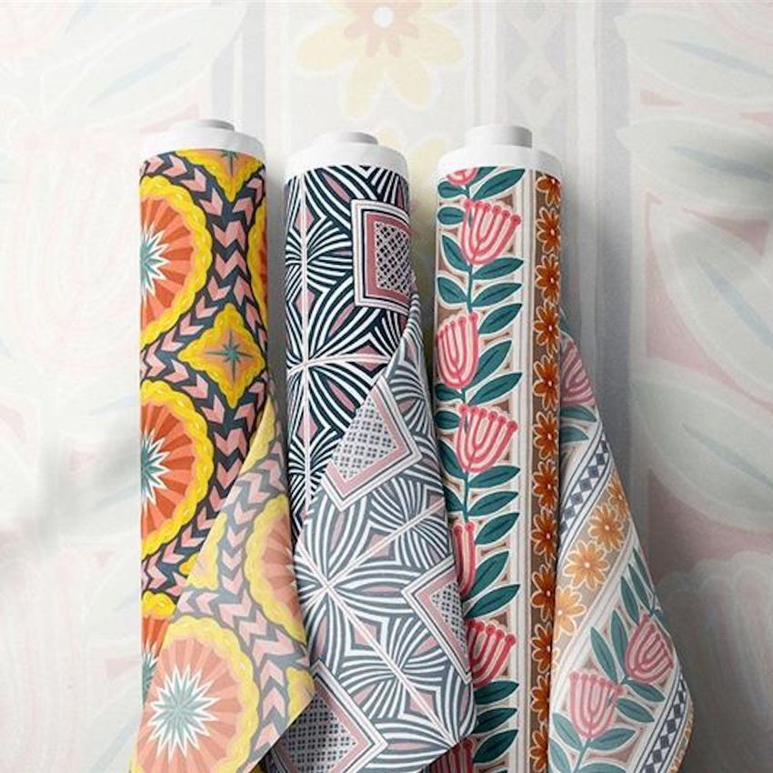 Fabric rolls mockup featuring three upright rolls with colorful geometric and floral patterns on a soft patterned background.