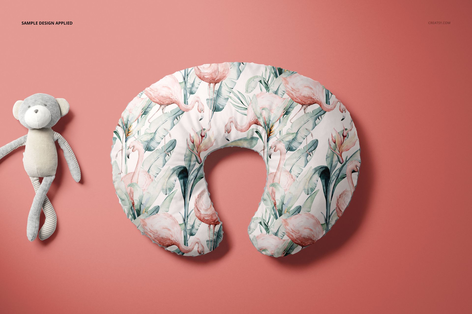 Mockup of a Boppy nursing pillow cover with a tropical flamingo design, displayed on a pink background beside a stuffed animal.