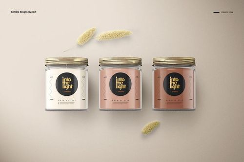 Jar candle PSD mockup featuring three glass jars with gold lids and decorative labels, arranged side by side.