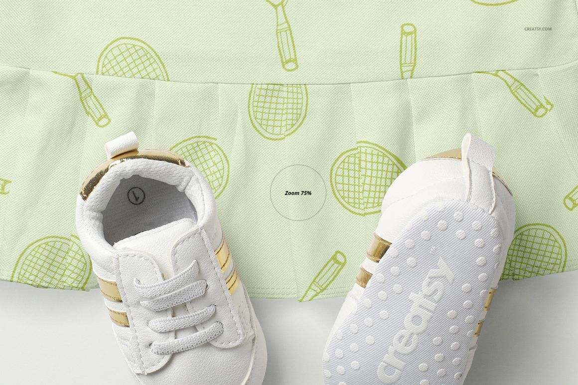 Front view of a light green polo dress mockup with tennis racket pattern, shown with a pair of white baby shoes.