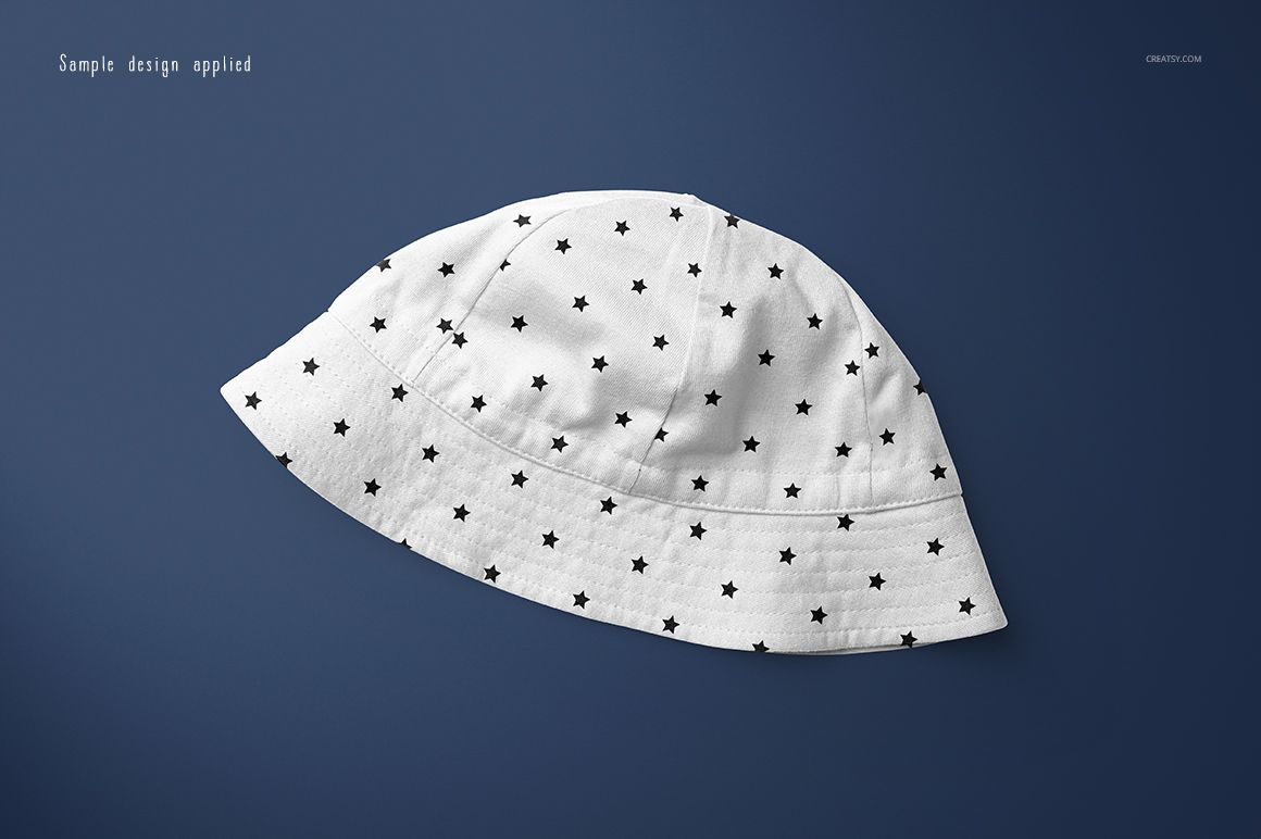White baby hat with black star pattern displayed on a solid dark blue background in a top view mockup.