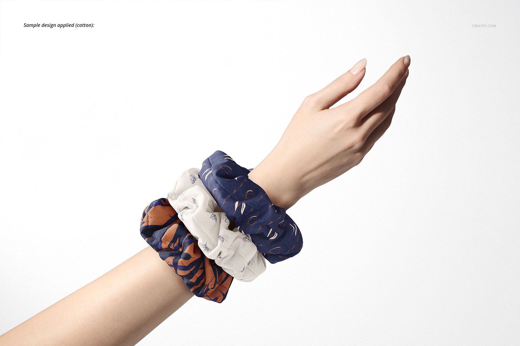 Fashion accessory mockup showing a hand with assorted colored hair scrunchies, displayed in a minimalist studio setting.