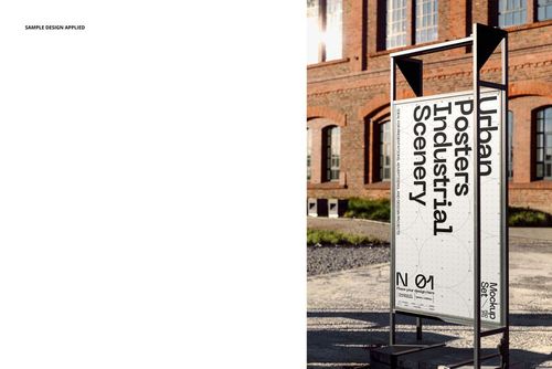 Front view of a vertical poster mockup on a metal stand, placed outside near a brick industrial building.