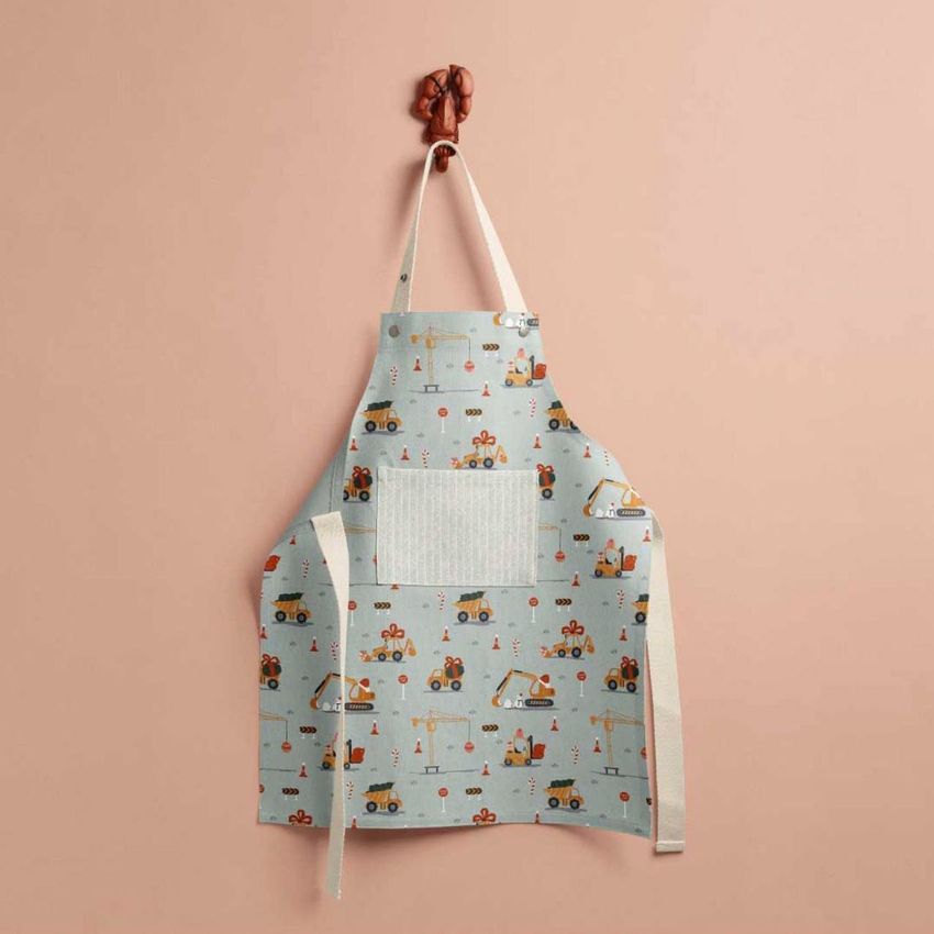 Kids apron mockup hanging on a wall, featuring a light blue fabric with playful construction vehicle patterns and a front pocket.