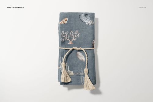 Cotton linen napkin mockup featuring ocean-themed illustrations, folded and secured with a decorative rope and tassels.