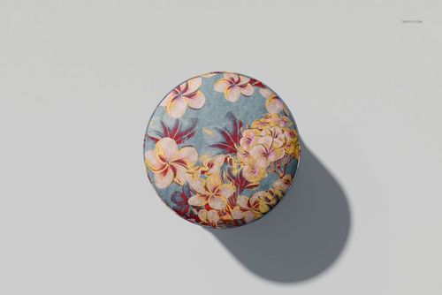 Top view of a fringed velvet footstool mockup with a multicolored floral design and soft shadow on a pale surface.