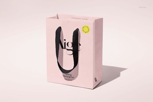 Single paper gift bag mockup with large black ribbon handles and minimalist design, photographed on a soft surface.