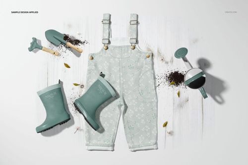 Children’s dungarees mockup with garden boots, spade, rake, and watering can, styled on a light wooden surface.