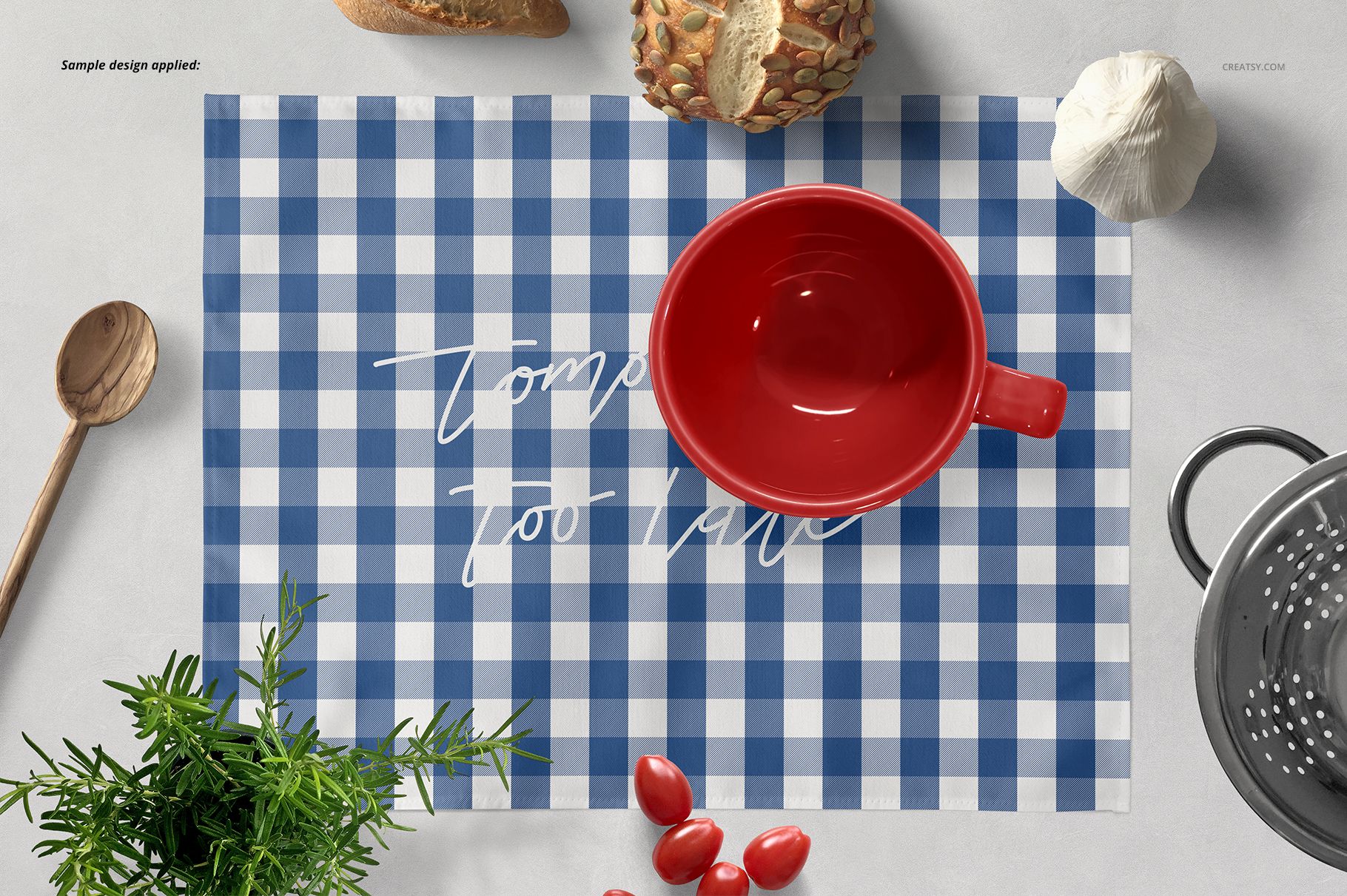 Blue and white checkered placemat mockup with a red bowl, bread, garlic, and herbs on a light surface.