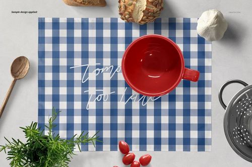 Blue and white checkered placemat mockup with a red bowl, bread, garlic, and herbs on a light surface.