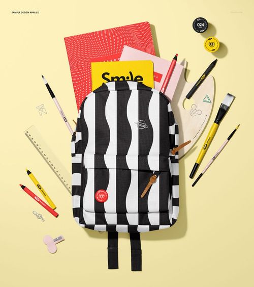 Black and white backpack mockup with various stationery items like notebooks, pens, and ruler arranged on yellow background.