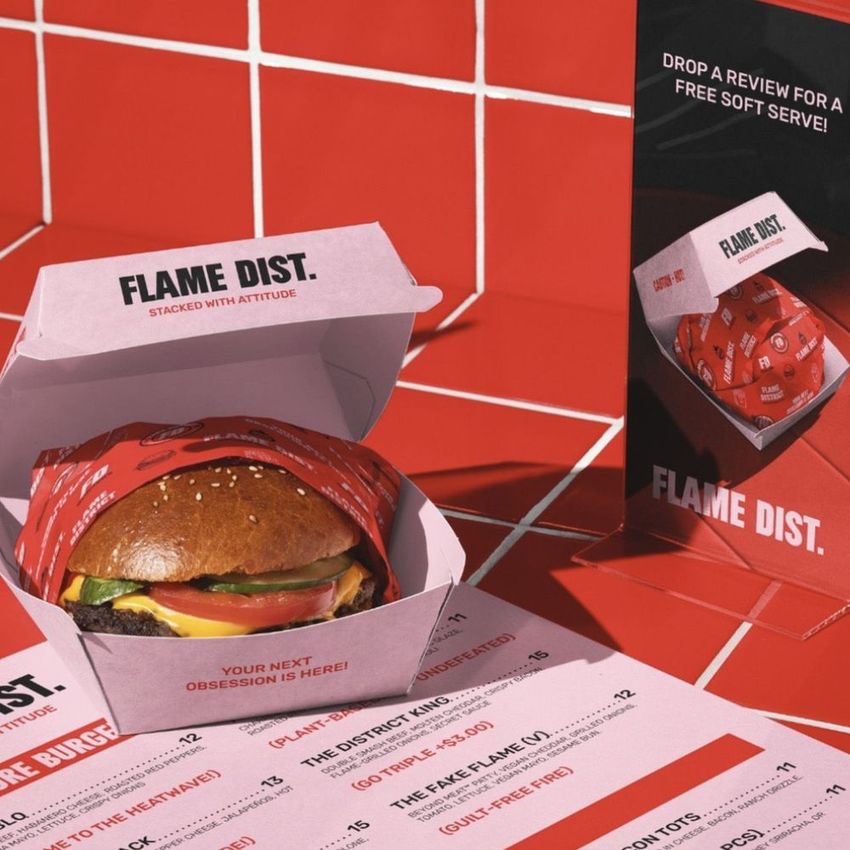 Burger bar menu mockup featuring a burger in a branded box, printed menu sheet, and tabletop display on a red tiled surface.