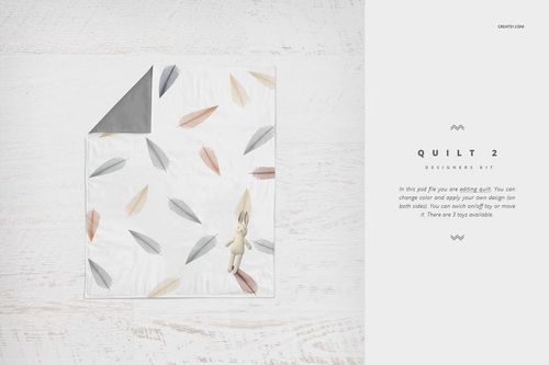 PSD mockup of a crib bedding quilt with gray backing and pastel feather prints, arranged flat with a toy bunny.