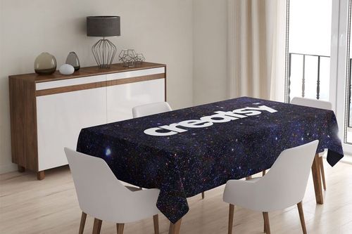 Tablecloth PSD mockup showing a cosmic-themed fabric with white text on a rectangular table in a contemporary interior.
