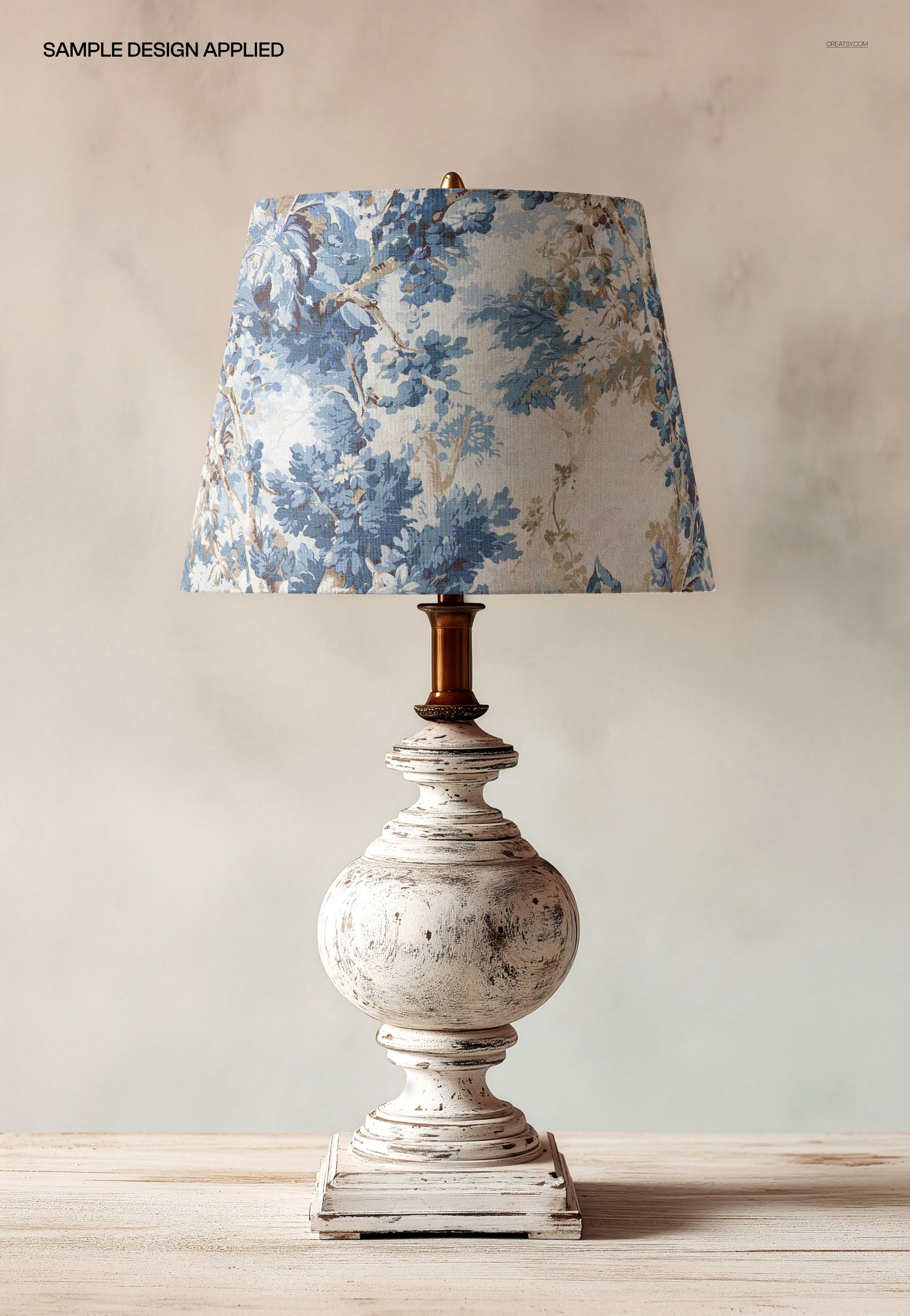 Classic table lamp mockup featuring a distressed white pedestal base and a blue floral lampshade, shown from the front.