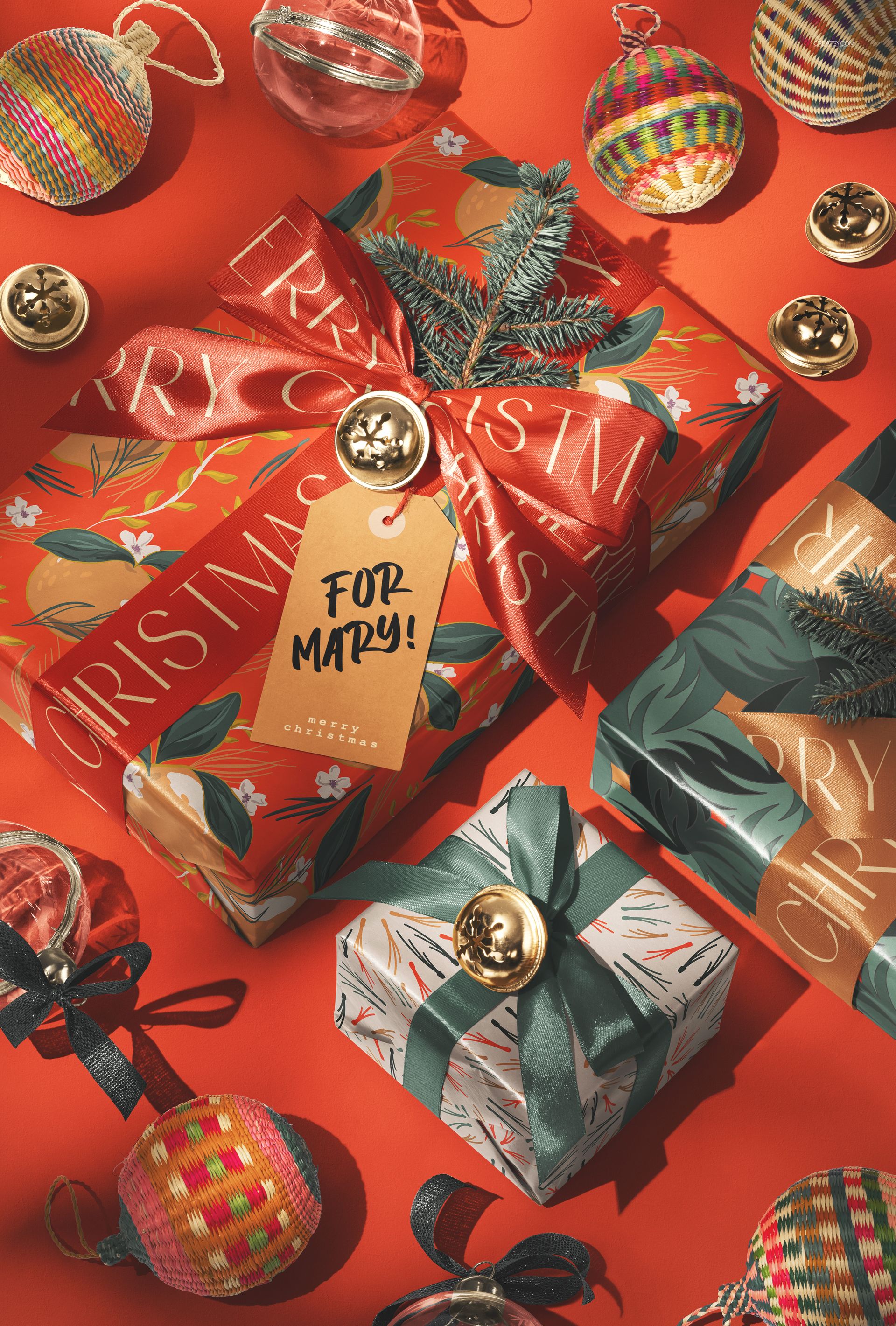 PSD mockup of holiday gift boxes with bows, ornaments, and a name tag, displayed on a vibrant red background.