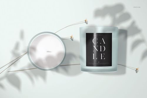 Mockup of a frosted glass candle featuring a black label, displayed with lid and delicate dried flower accents.