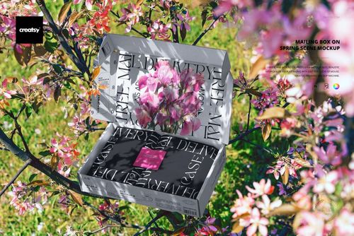 Mailing box mockup with floral spring branches, featuring large black lettering on the lid, viewed from above.