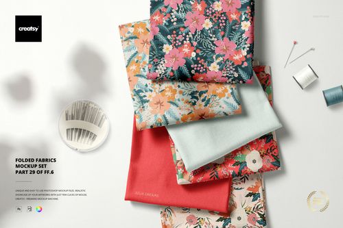 Stack of folded fabric pieces in various floral and solid patterns, shown from a top view with sewing props nearby.