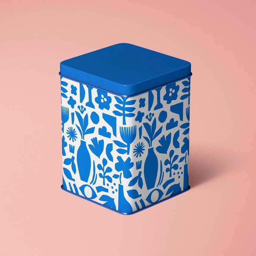 Tin canister mockup featuring a blue and white floral pattern, shown on a pastel pink background with soft lighting.