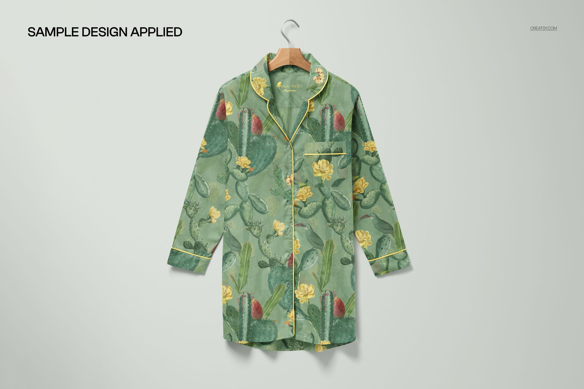 Front view of a nightdress mockup with a green cactus and yellow flower pattern, hanging on a wooden hanger.