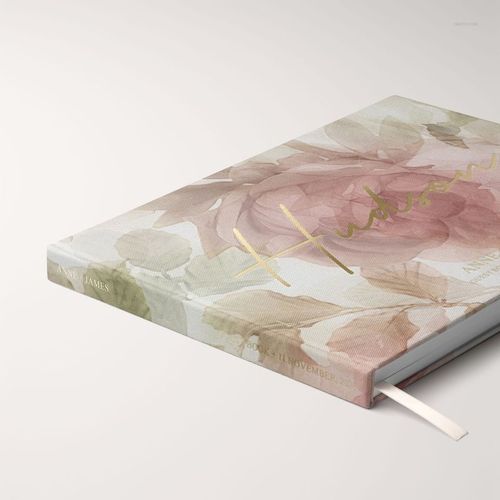 Angled close-up of a landscape wedding guest book mockup featuring soft floral patterns and metallic gold text on the cover.