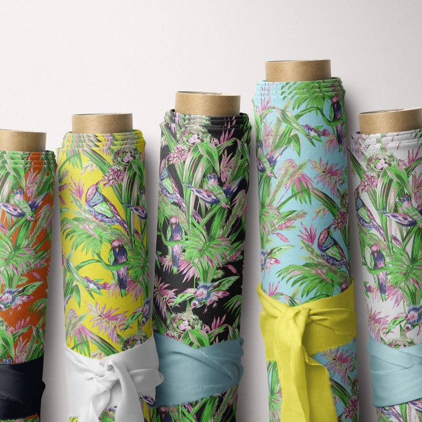 Fabric rolls mockup featuring five upright rolls with tropical bird and foliage patterns in vibrant colors against a white background.