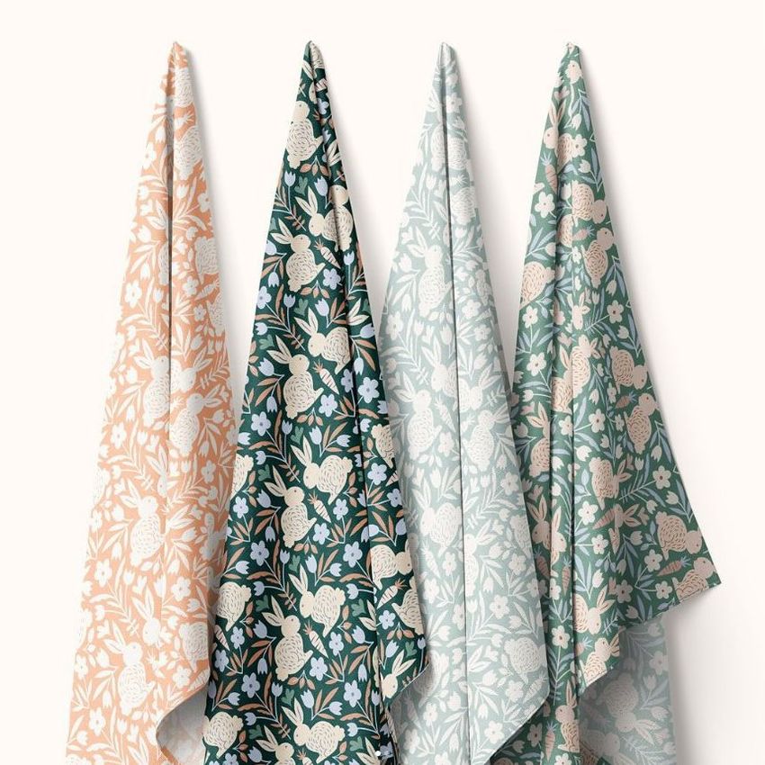 Four hanging fabric mockups displayed side by side, each featuring a repeating bunny and floral pattern in pastel colors.
