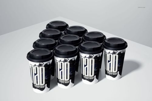 PSD mockup showing several paper cups with black tops and modern monochrome designs, viewed from a slightly angled perspective.