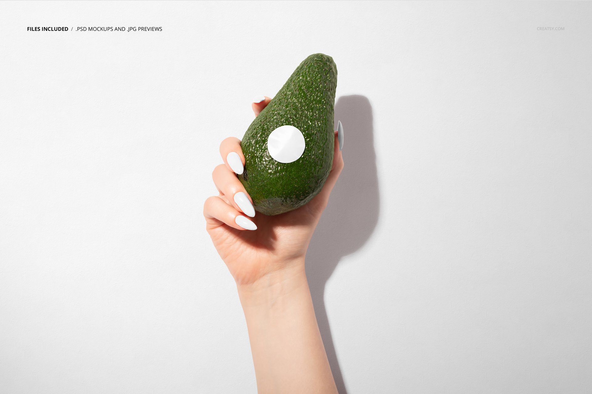 Avocado fruit with a blank round sticker held by a hand, displayed in a packaging mockup scene with a simple background.