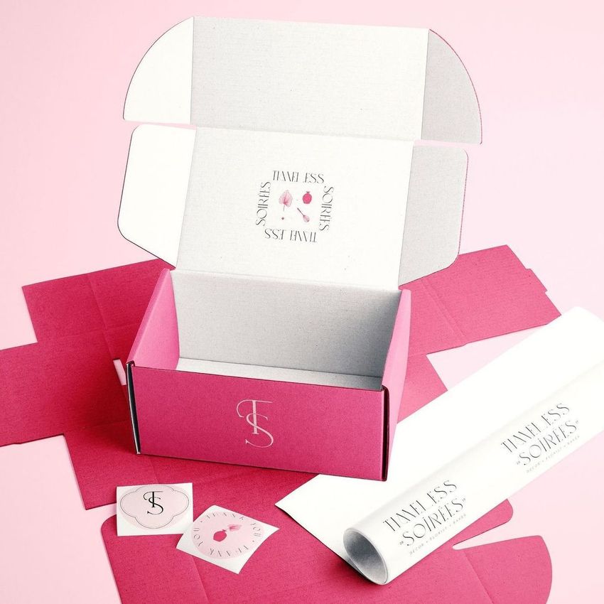 Mailing box mockup with a pink and white color scheme, open to show custom printed interior and matching branded stickers.