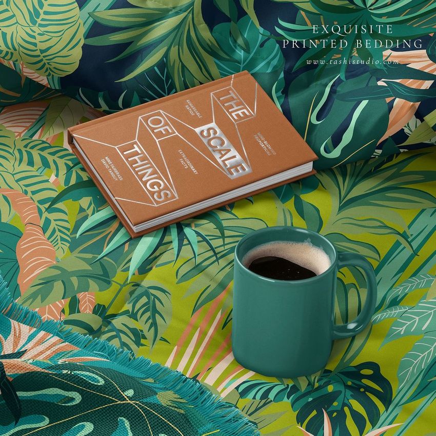 Microfiber comforter mockup featuring a tropical leaf pattern, with a brown book and green mug of coffee on the bedding.