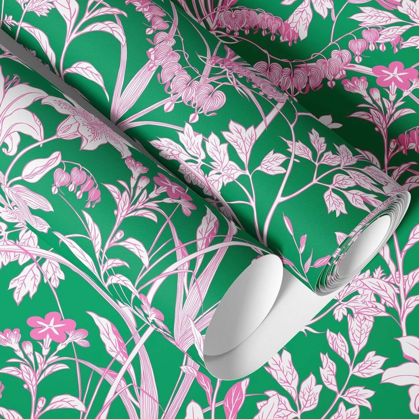 Paper wallpaper mockup featuring rolled sheets with a pink floral pattern on a green background, viewed from above.