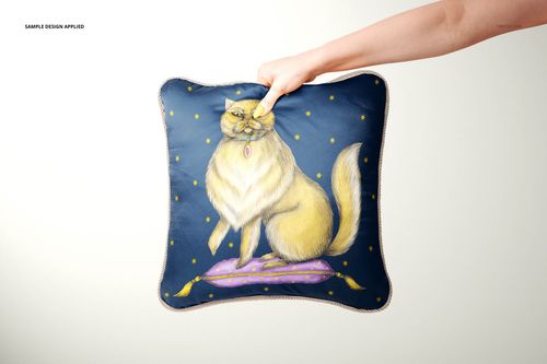 Front view of a silk cushion mockup with braid trim, decorated with a cat artwork and star-like yellow accents.