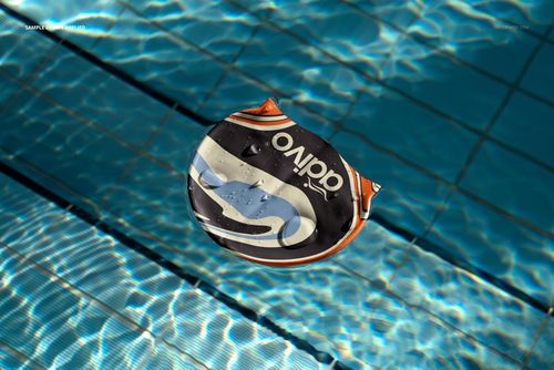 Mockup of a swim cap featuring bold graphic design, floating in a swimming pool with rippling water surface.