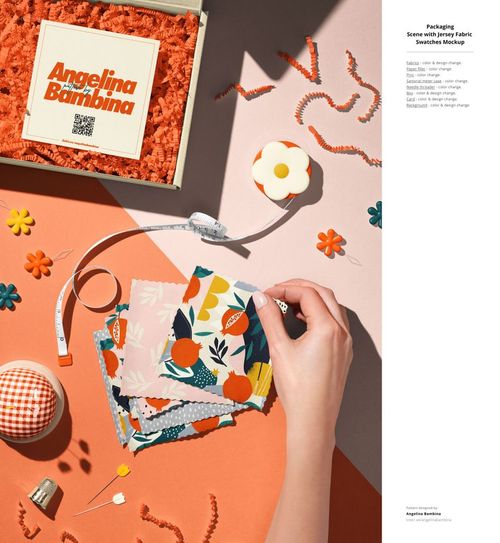 PSD mockup featuring a hand selecting patterned fabric swatches, surrounded by orange box, pins, and thread.