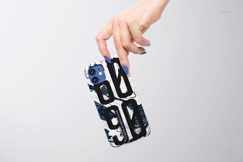 Front view of an iPhone 12 glossy snap case mockup with large black letters and a marbled white pattern, held by hand.