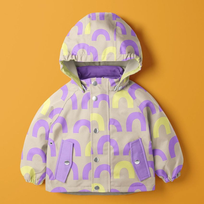 Kids rainwear mockup featuring a hooded jacket with purple and yellow arch patterns on a beige background, set on an orange surface.