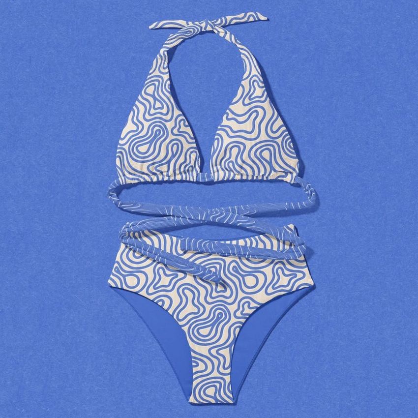 High waisted bikini mockup set displayed flat on a textured blue background, featuring abstract wavy line patterns in white and blue.