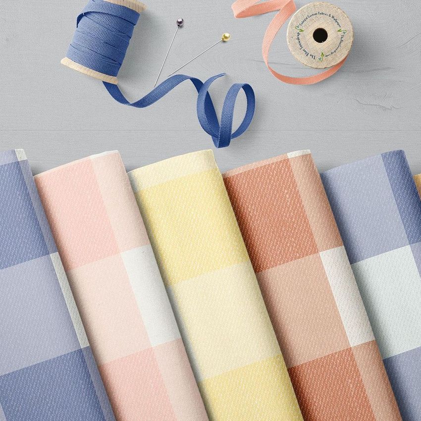 Folded fabrics mockup featuring five pieces of fabric with pastel check patterns arranged in a row on a light surface.