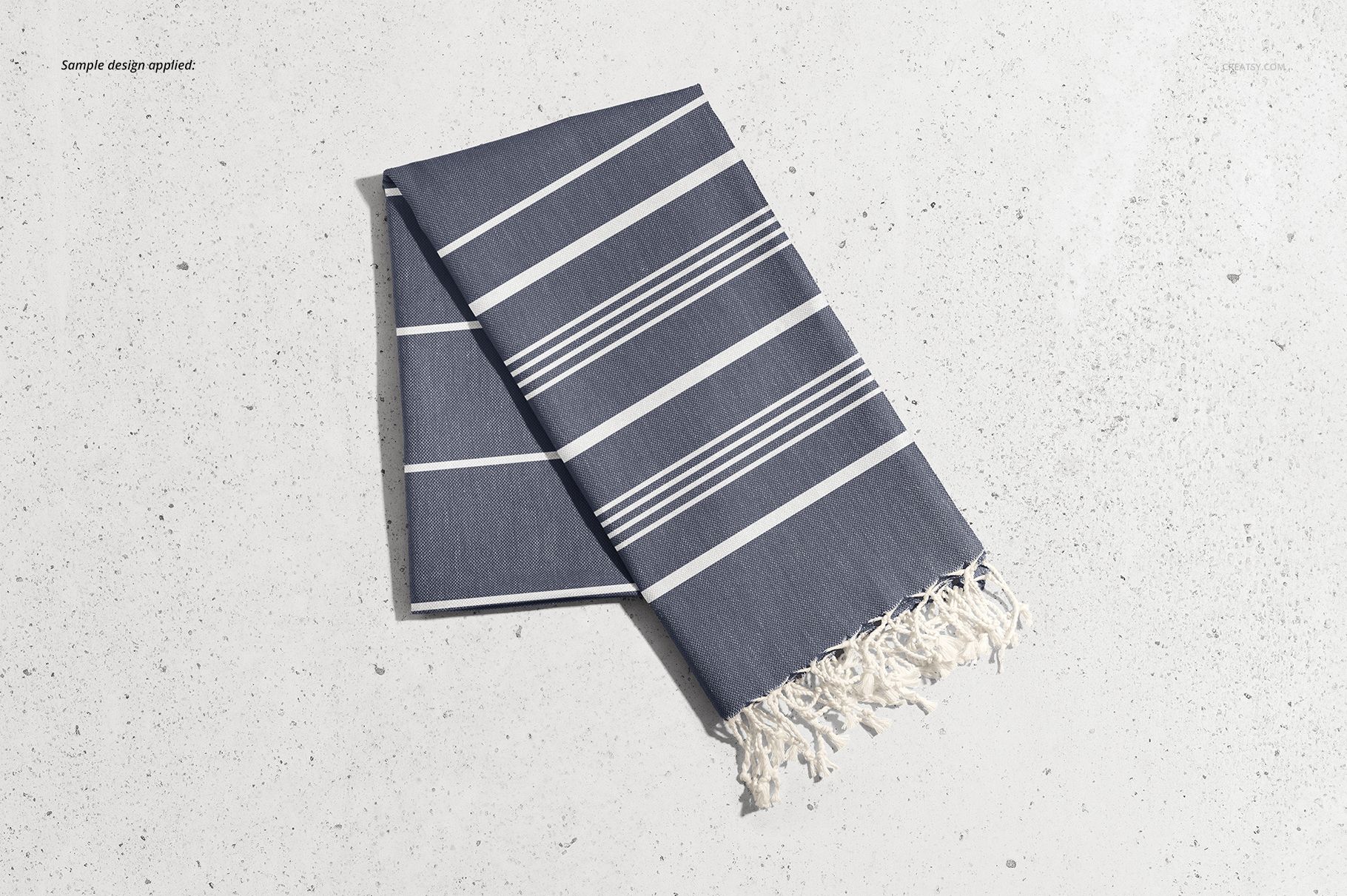 Turkish towel mockup featuring white tassels and bold horizontal stripes, displayed from a top view on a concrete surface.