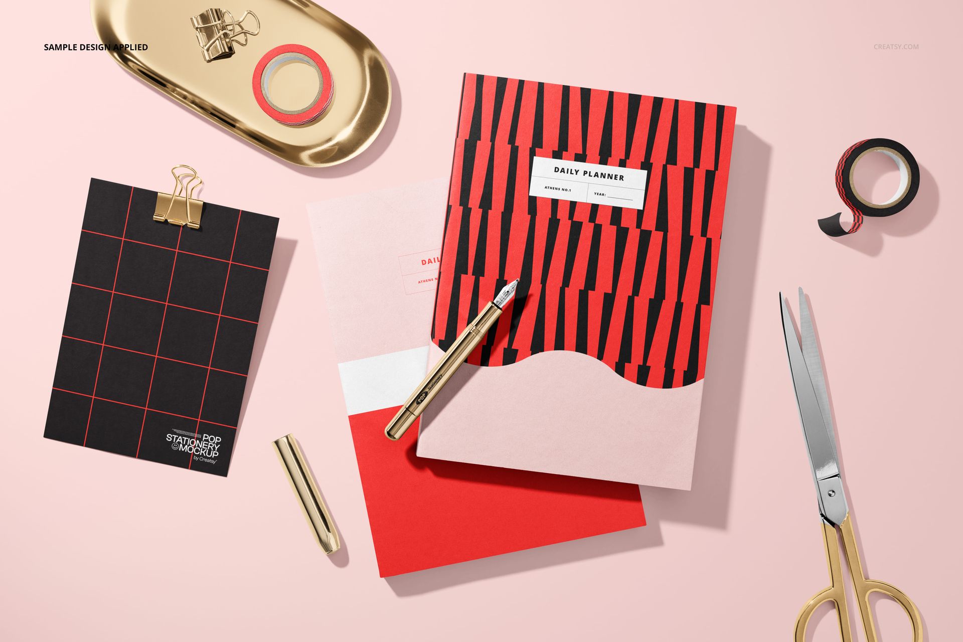 PSD mockup displaying two planners with geometric patterns, a card, and gold desk accessories on a pink background.