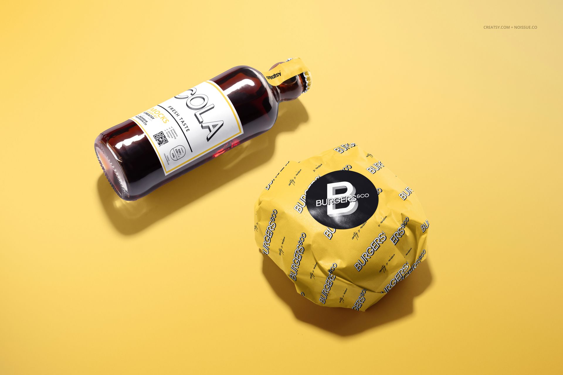 Yellow food safe paper mockup featuring a wrapped burger and a cola bottle placed on a plain yellow background.