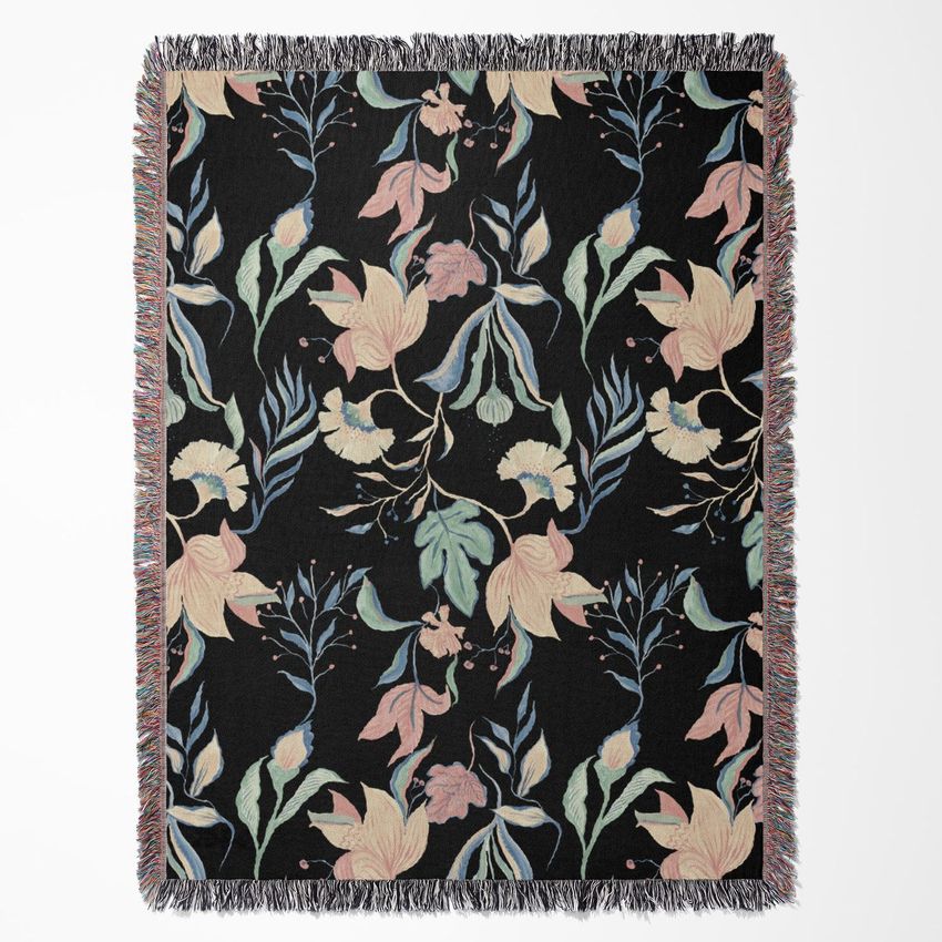 Woven throw blanket mockup featuring a dark background with a pastel floral pattern and multicolored fringe edges, shown flat.