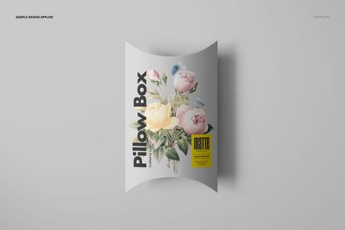 Top view of a matte pillow box mockup featuring pastel flower artwork and black text, placed on a plain surface.
