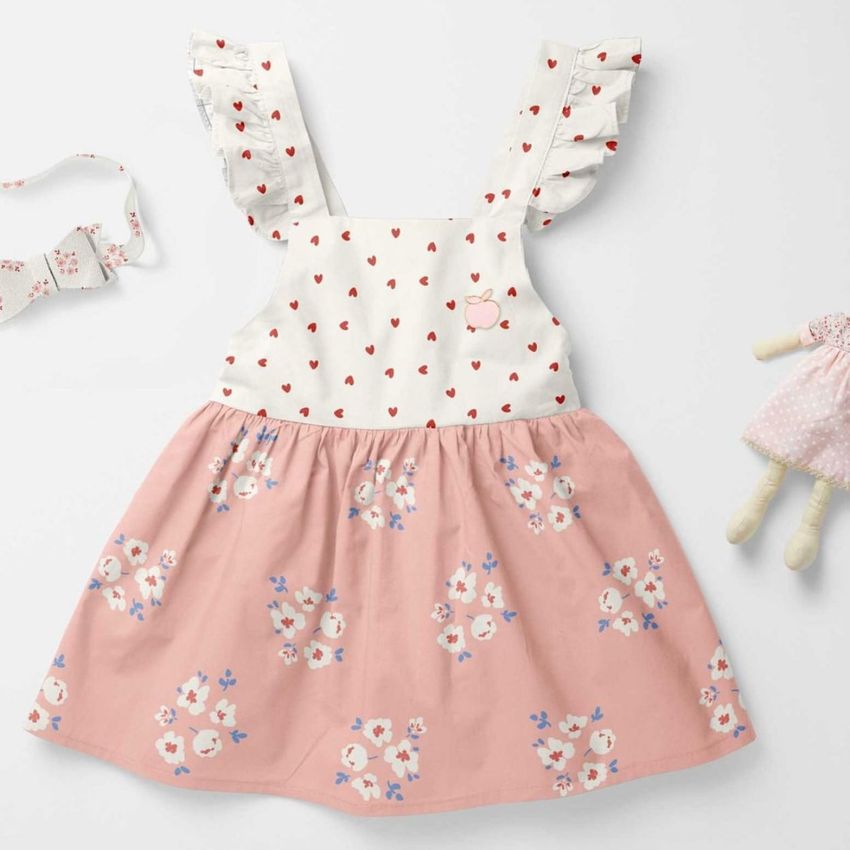 Baby dress mockup featuring a white top with small red hearts and a pink skirt with floral patterns, displayed on a light surface.
