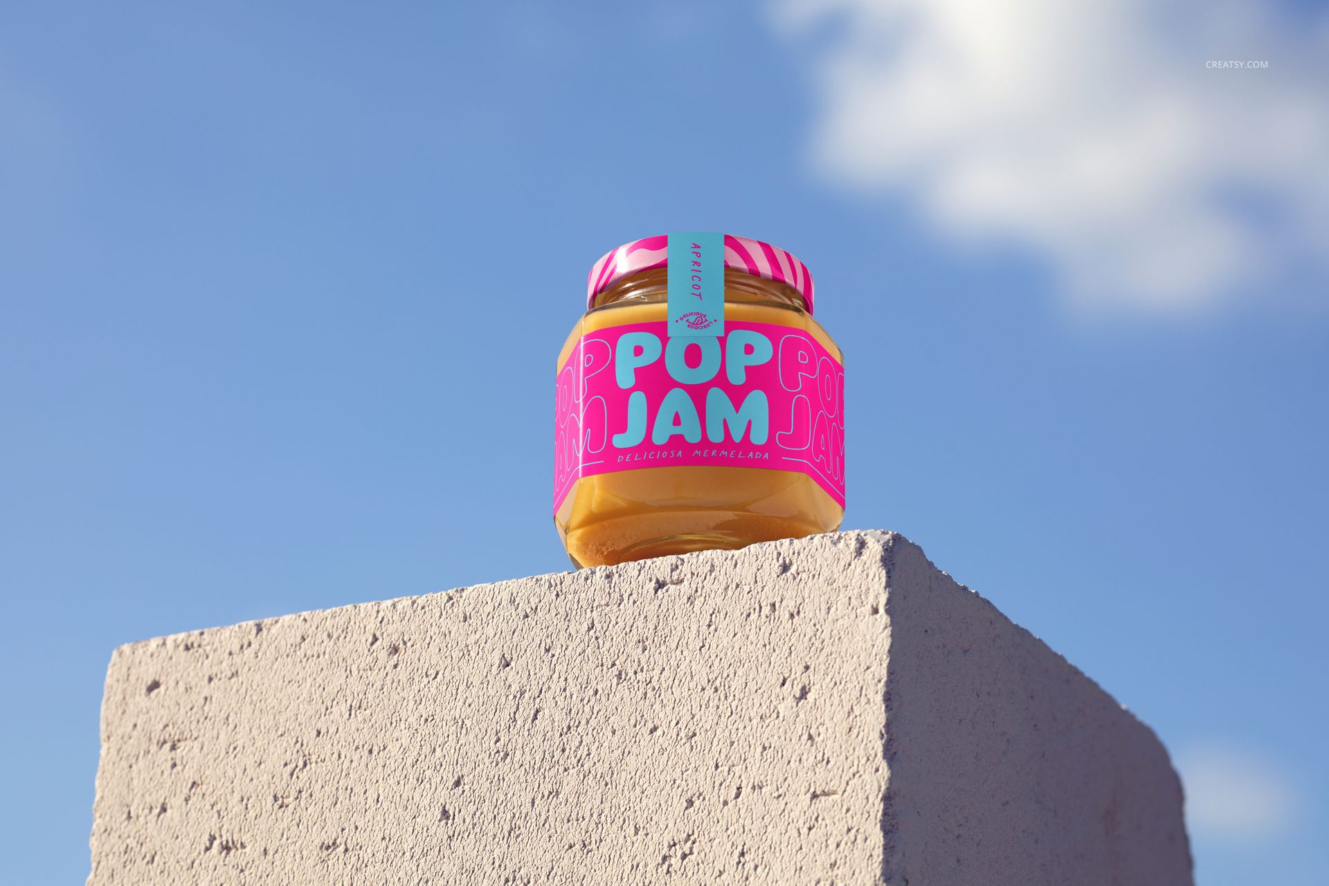 PSD mockup of a jam jar with vibrant packaging, sitting atop a gray block outdoors under a partly cloudy sky.