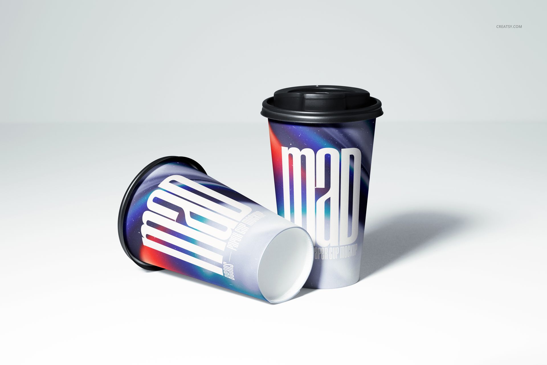 Paper cup mockup set showing two cups with colorful gradient patterns and prominent white lettering on a light surface.